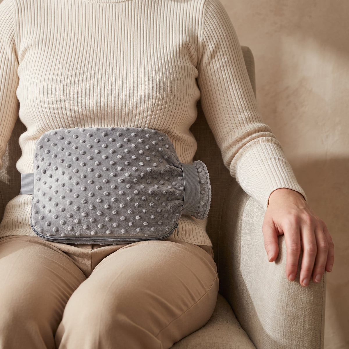 Bouillotte ceinture grise portée à la taille par-dessus un vêtement