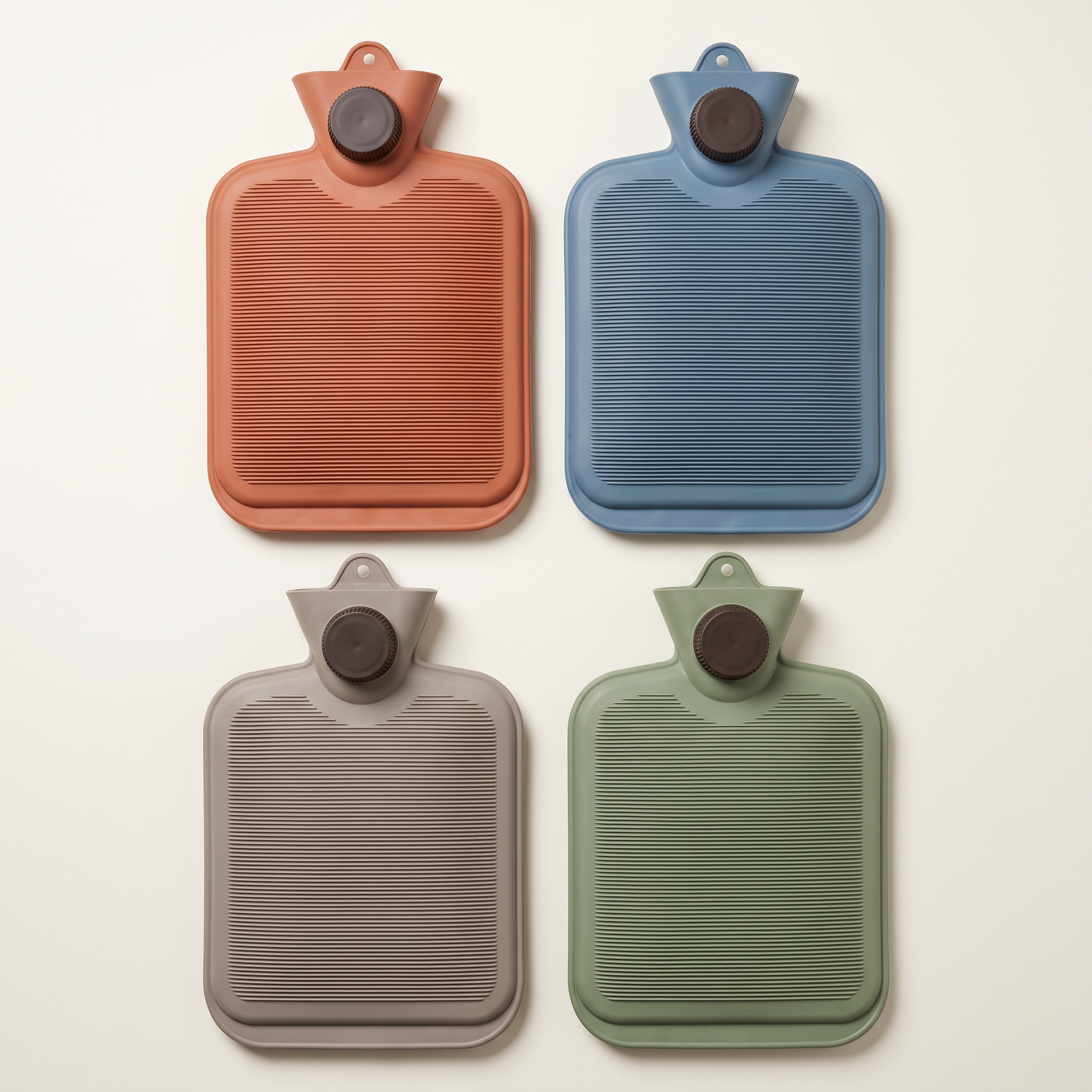 Les quatre coloris de bouillotte sans housse : terracotta, bleu, vert et gris